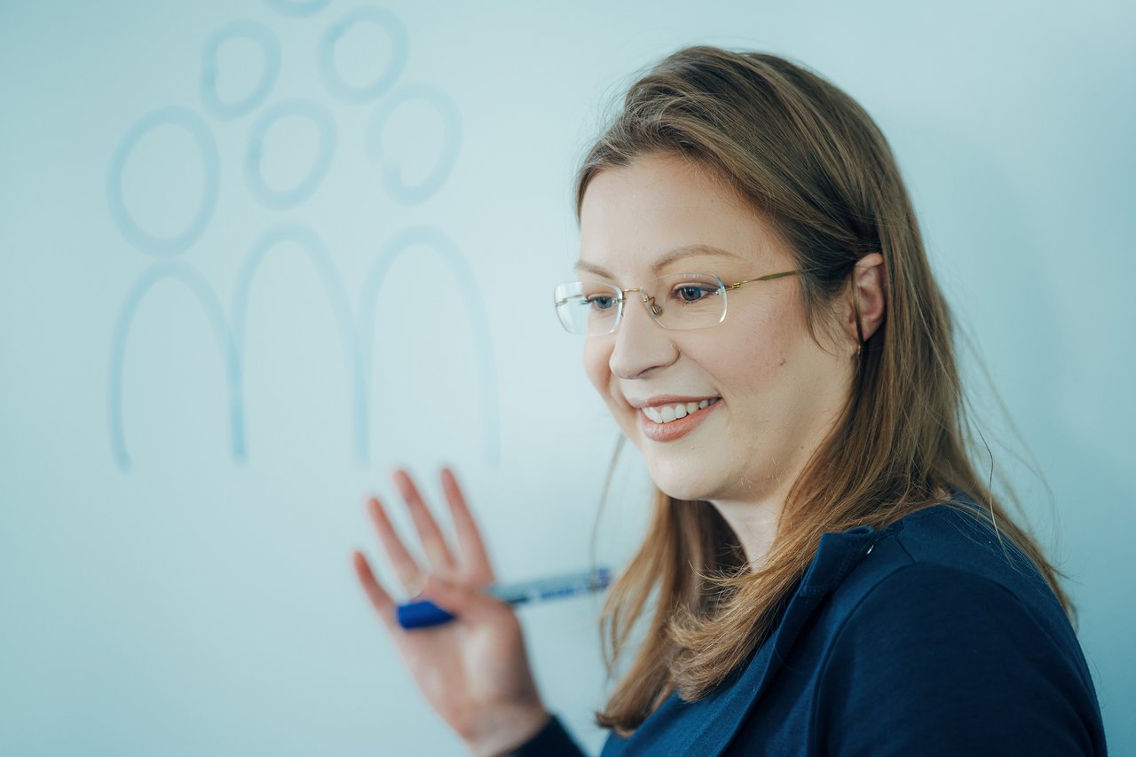 hms-initiativen-mitgestaltung-austausch Mitarbeiterin von HMS wirbt im Austausch vor einem Whiteboard für usere Initiativen